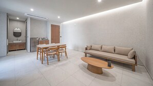 A modern living space with a dining area, sofa, and a kitchen in the background. - Giant Hotel (Daegu)