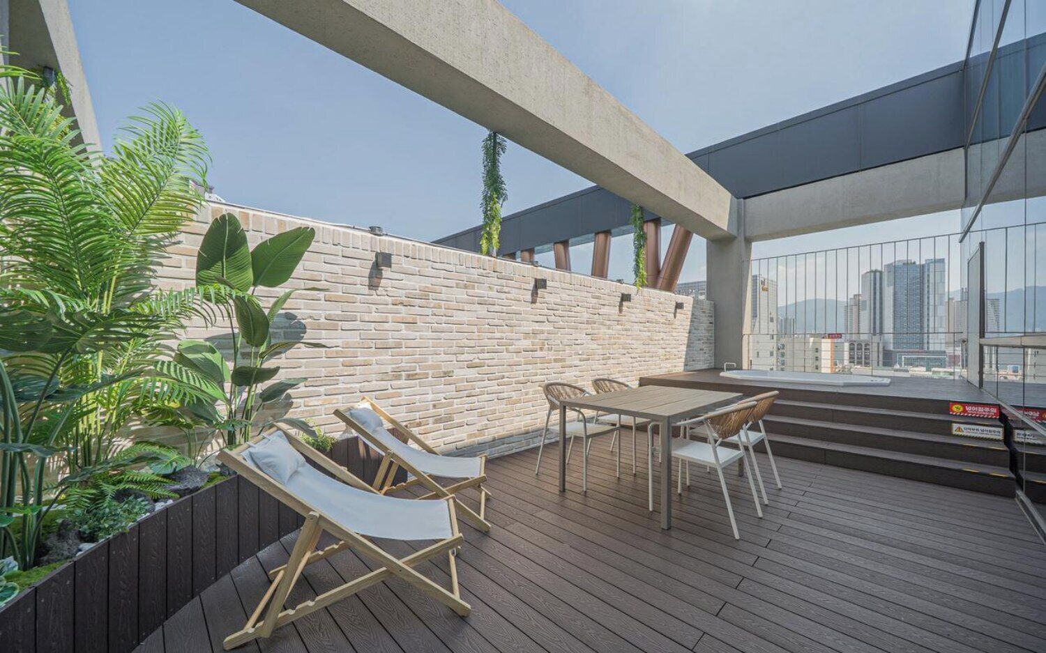 Una terrazza esterna con parete in mattoni, pavimento in legno e zone relax.