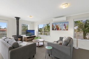 Ein modernes Wohnzimmer mit Kamin, Fernseher und einem Gemälde von Surfbrettern.