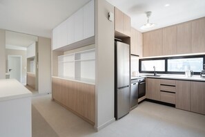 Eine moderne Küche mit hellen Holzschränken, einem Edelstahlkühlschrank und einem Fenster für natürliches Licht.