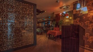Un interior de restaurante con un separador decorativo, suelo de madera e iluminación colgante.