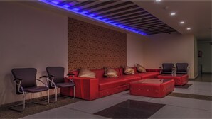 Un área de estar moderna con un sofá seccional rojo, dos sillones negros y una mesa de centro de vidrio.