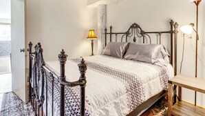 A bedroom with a bed, a bedside table, a lamp, and a door.