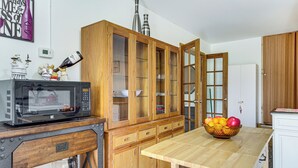 A kitchen with wooden cabinets, a microwave, and a fruit bowl on the table.