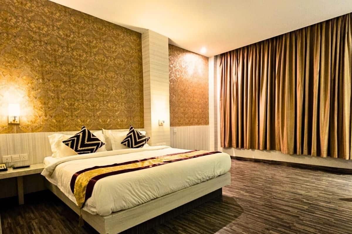 A hotel room with a large bed, a nightstand, a wall with a textured pattern, and a curtain on the window.