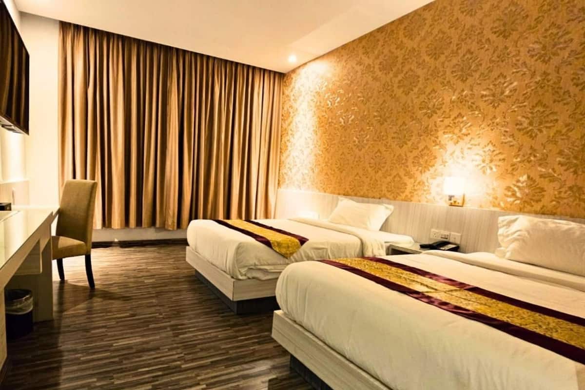 A hotel room with two beds, a desk, and a chair.