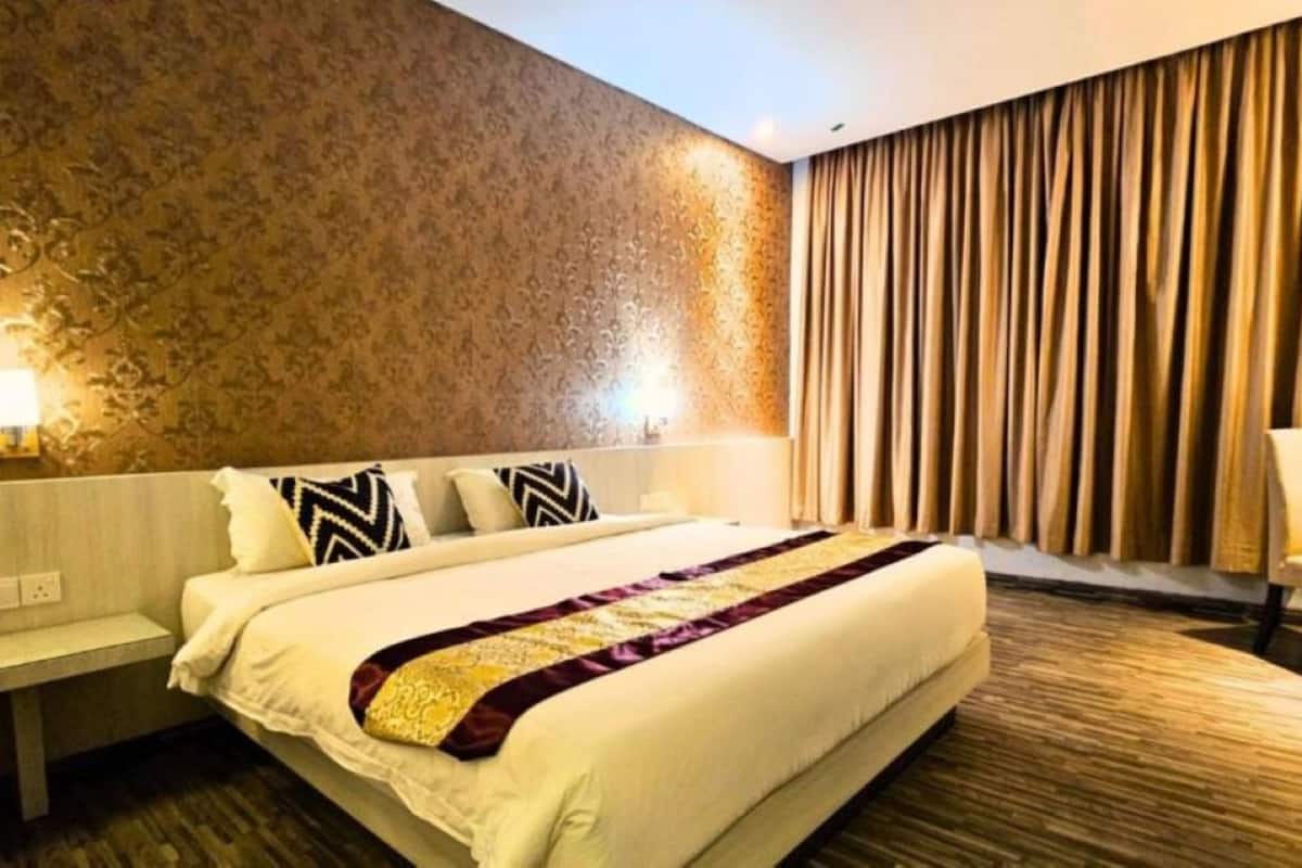 A hotel room with a large bed, a nightstand, a lamp, and a curtain.