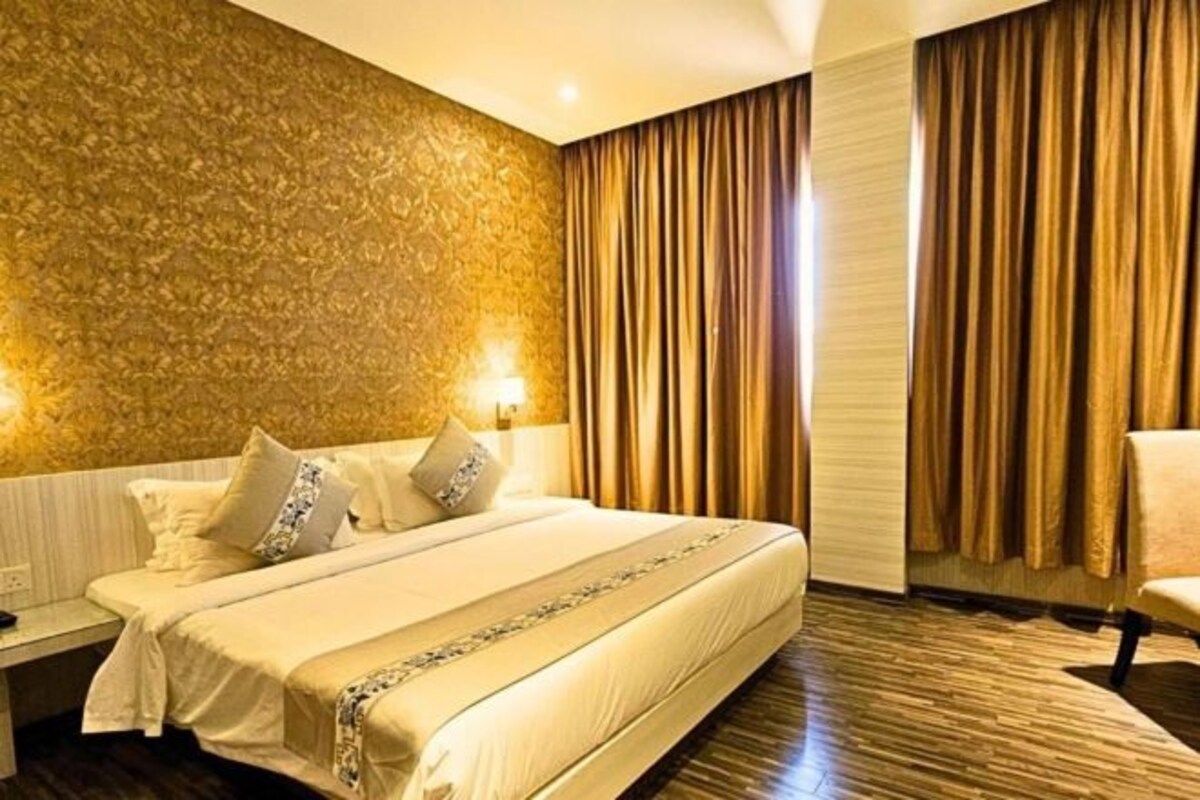 A hotel room with a large bed, a nightstand, a chair, and a textured wall.