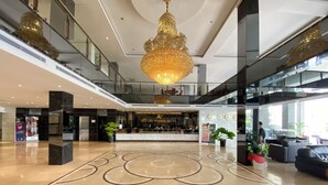 Een hotel lobby met een receptiebalie, een grote kroonluchter en een modern design.