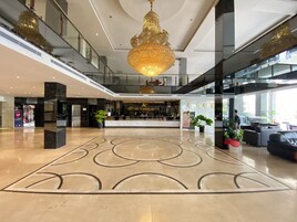 Un vestíbulo de hotel con mostrador de recepción, una lámpara de araña grande y un diseño moderno.