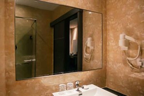 A bathroom with a large mirror, a sink, and a hairdryer mounted on the wall. - Alltrue Sydney Hotel Batam Center (Batam)