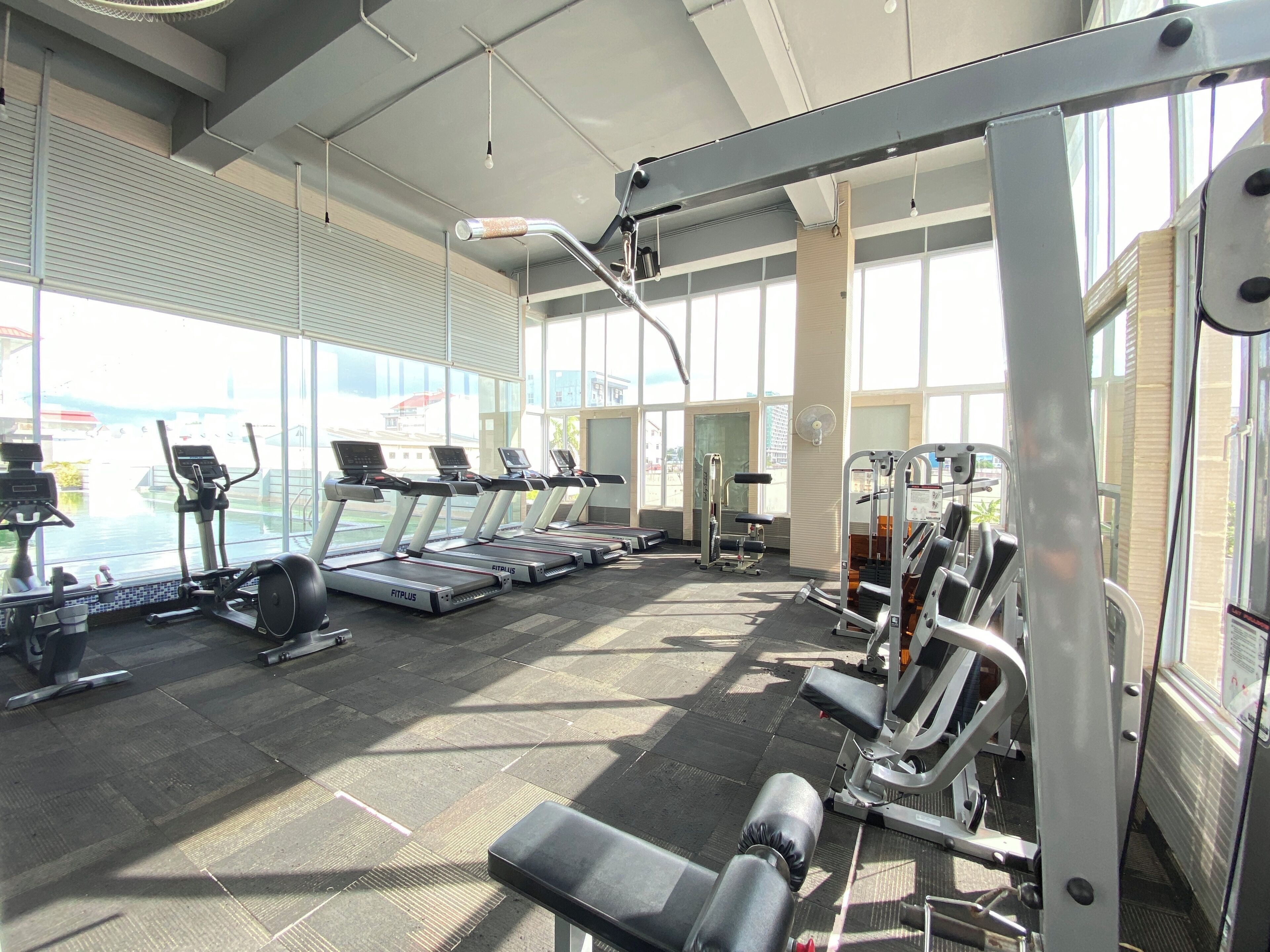 A gym with treadmills, weight machines, and a large window providing a view of the outside.