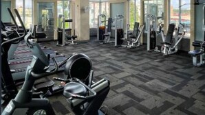 Een sportschool met trainingsapparatuur, grote ramen en uitzicht op de stad.