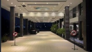 Een gang met een betegelde vloer, een plafond met een decoratief paneel in het midden, en twee borden met daarop 'niet parkeren'.