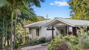 A single-story house with a porch, surrounded by dense vegetation and a clear sky. - Quiet Ninderry Cottage with Peaceful Rural Outlook (Ninderry)