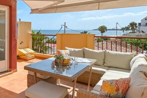 A balcony with a wicker table, white sofa, and a view of the sea. - Denimar - Denia, Costa Blanca (Denia)