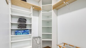 Um closet amplo com prateleiras abertas, cabideiro e piso de madeira.