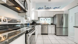 Uma cozinha moderna com armários brancos, eletrodomésticos de aço inoxidável e piso ladrilhado.