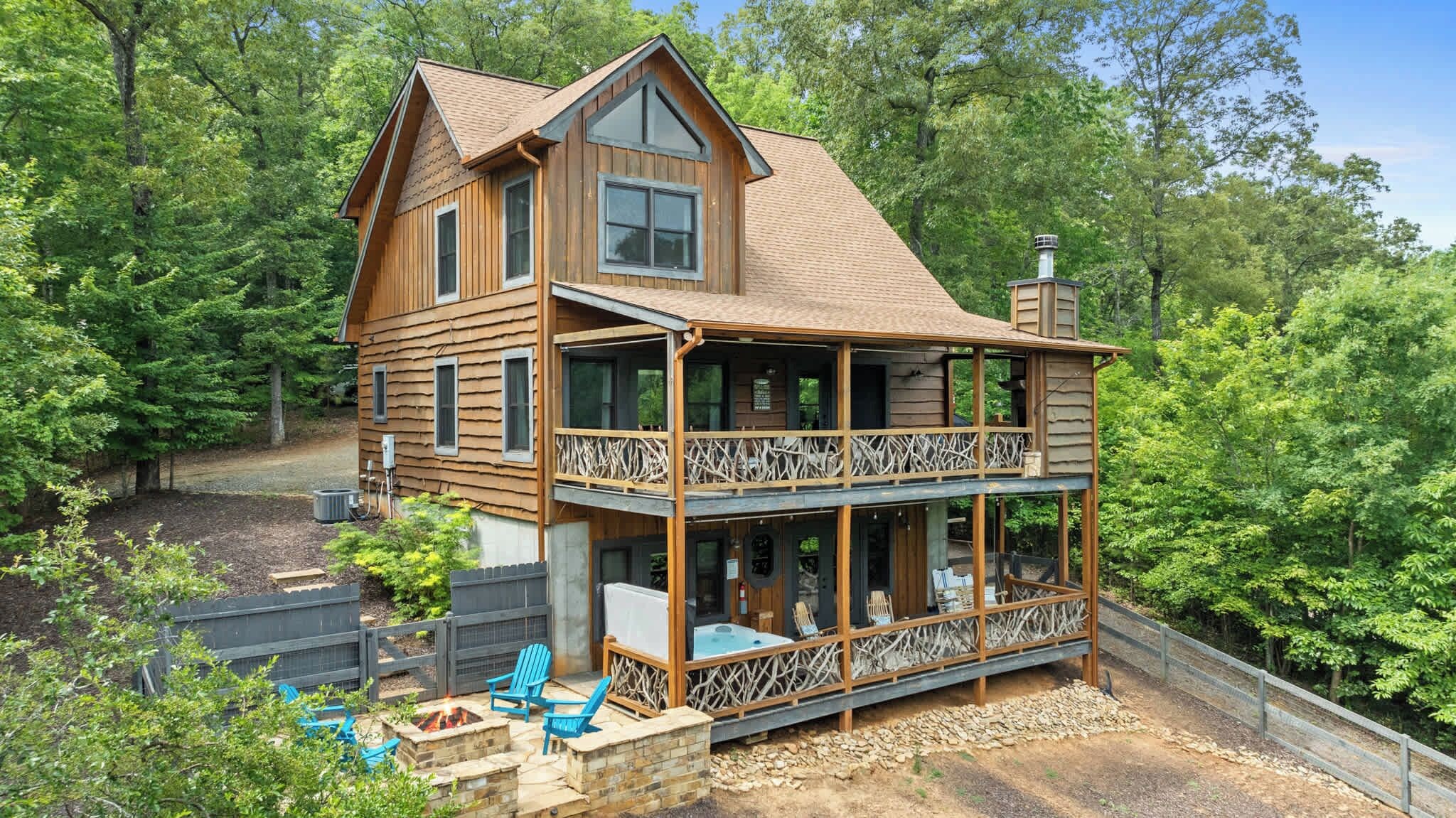 Une cabane en bois à deux étages, dotée d’un balcon et entourée d’arbres.