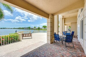 A covered patio with a view of a lake, outdoor seating, and a railing.