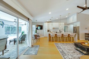 A modern kitchen with white cabinets, a central island with bar stools, and a dining area with a table and chairs.
