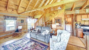 A log cabin interior with a living room, a staircase, and a kitchen area. - 2 Mi to Mabry Mill: Mtn-View Cabin w/ Porch! (Meadows of Dan)