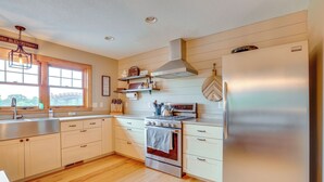 Een moderne keuken met houten kastjes, roestvrijstalen apparatuur en een groot raam voor natuurlijk licht.