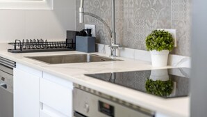 Eine moderne Küche mit doppelter Spüle, Edelstahlarmatur und Spritzschutz mit geometrischem Muster.