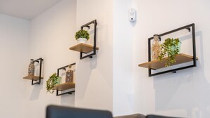 Ein Wohnzimmer mit einer Ledersofa, drei Wandregalen mit Pflanzen und einer weißen Wand.