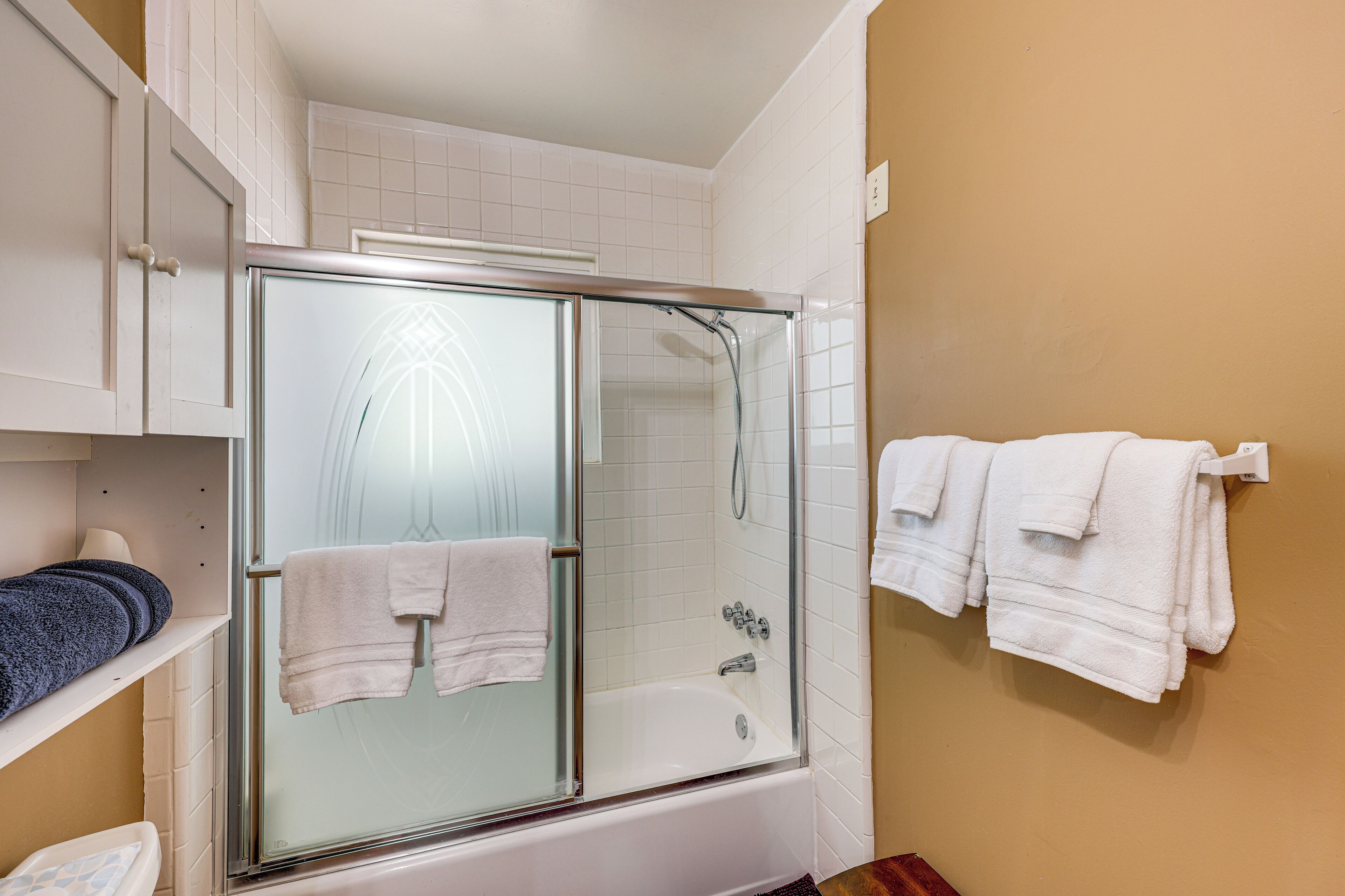 A bathroom with a glass-enclosed shower, a bathtub, and towels on a rack.