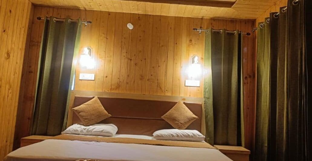 A wooden-paneled room with a bed, two wall-mounted lights, and curtains.