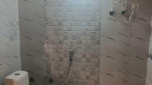 A small bathroom with a toilet, a shower, and a water heater. - Harsil apple homestay (Bhatwari)