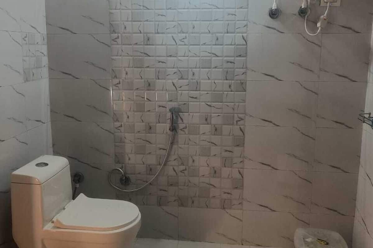 A small bathroom with a toilet, a shower, and a water heater.