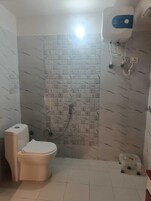 A small bathroom with a toilet, a shower, and a water heater.