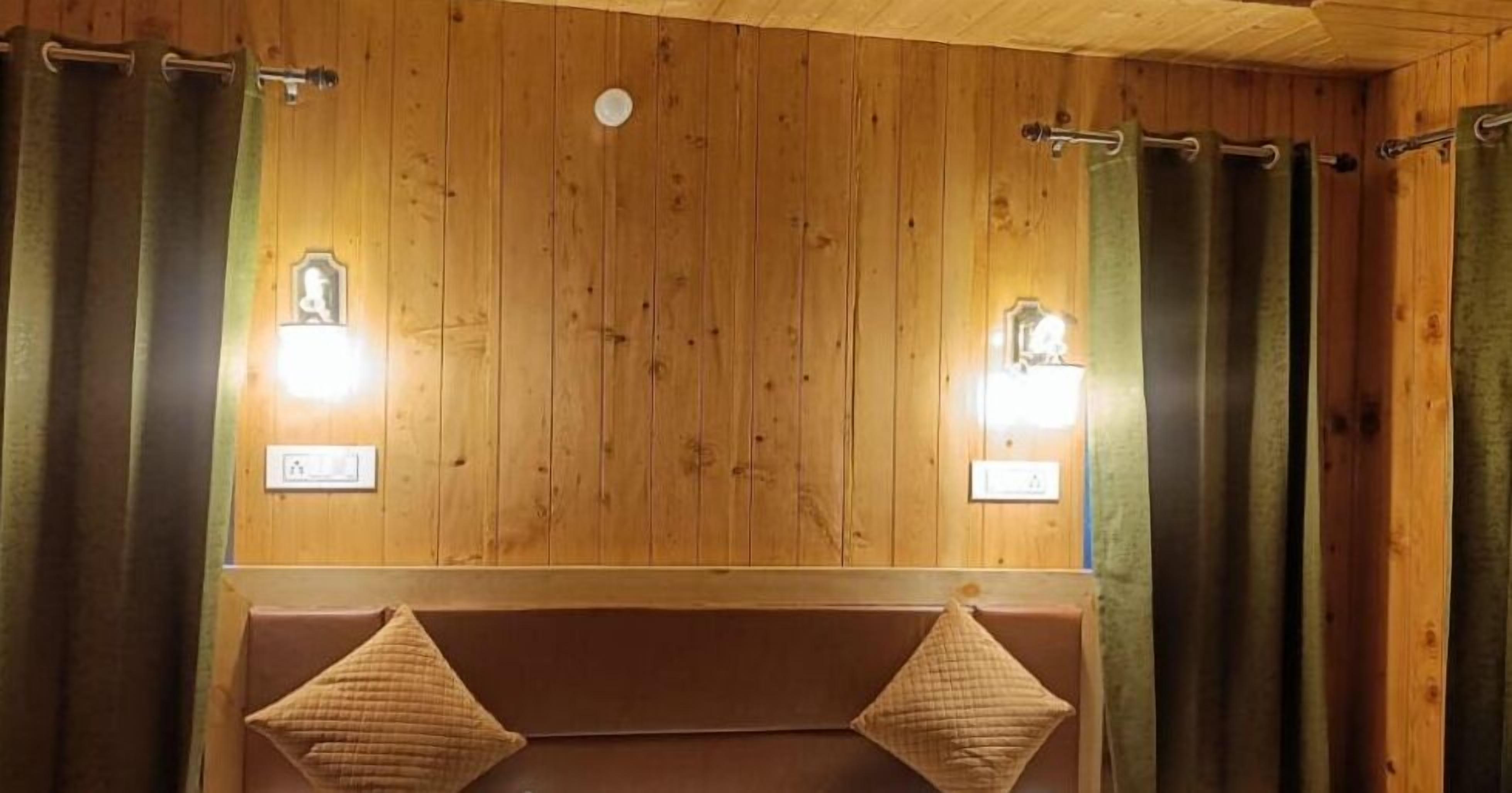 A wooden cabin-style bathroom with two wall-mounted lights, a bench, and a towel rack.