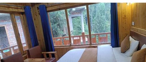 A wooden room with a bed, a bench, and large windows.