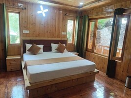 A wooden bedroom with a large bed, two bedside tables, and a window with curtains.