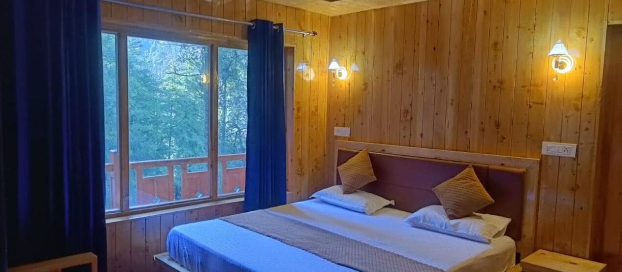 A wooden-paneled room with a bed, two wall sconces, and a window with curtains.