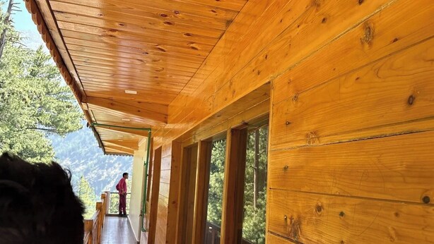 A wooden corridor with large windows and a balcony overlooking a mountainous landscape. - Harsil apple homestay (Bhatwari)