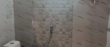 A small bathroom with a toilet, a shower, and a water heater mounted on the wall.