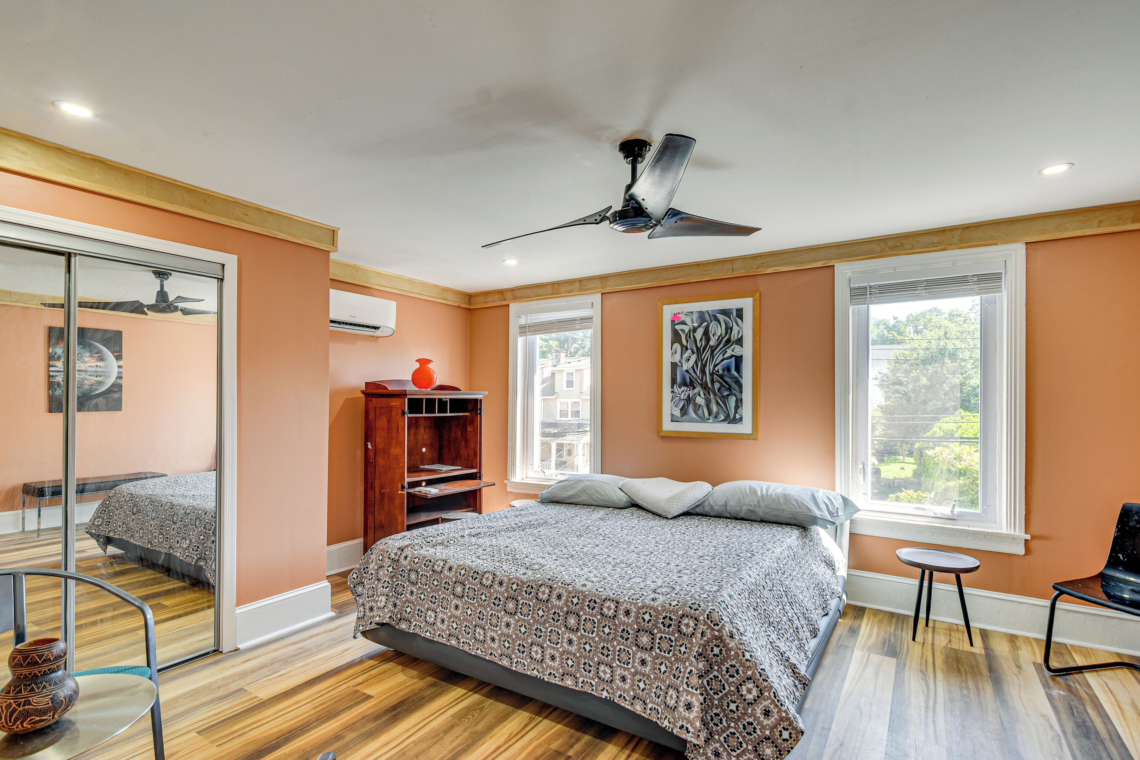 A bedroom with a bed, a ceiling fan, a window, and a wooden floor.