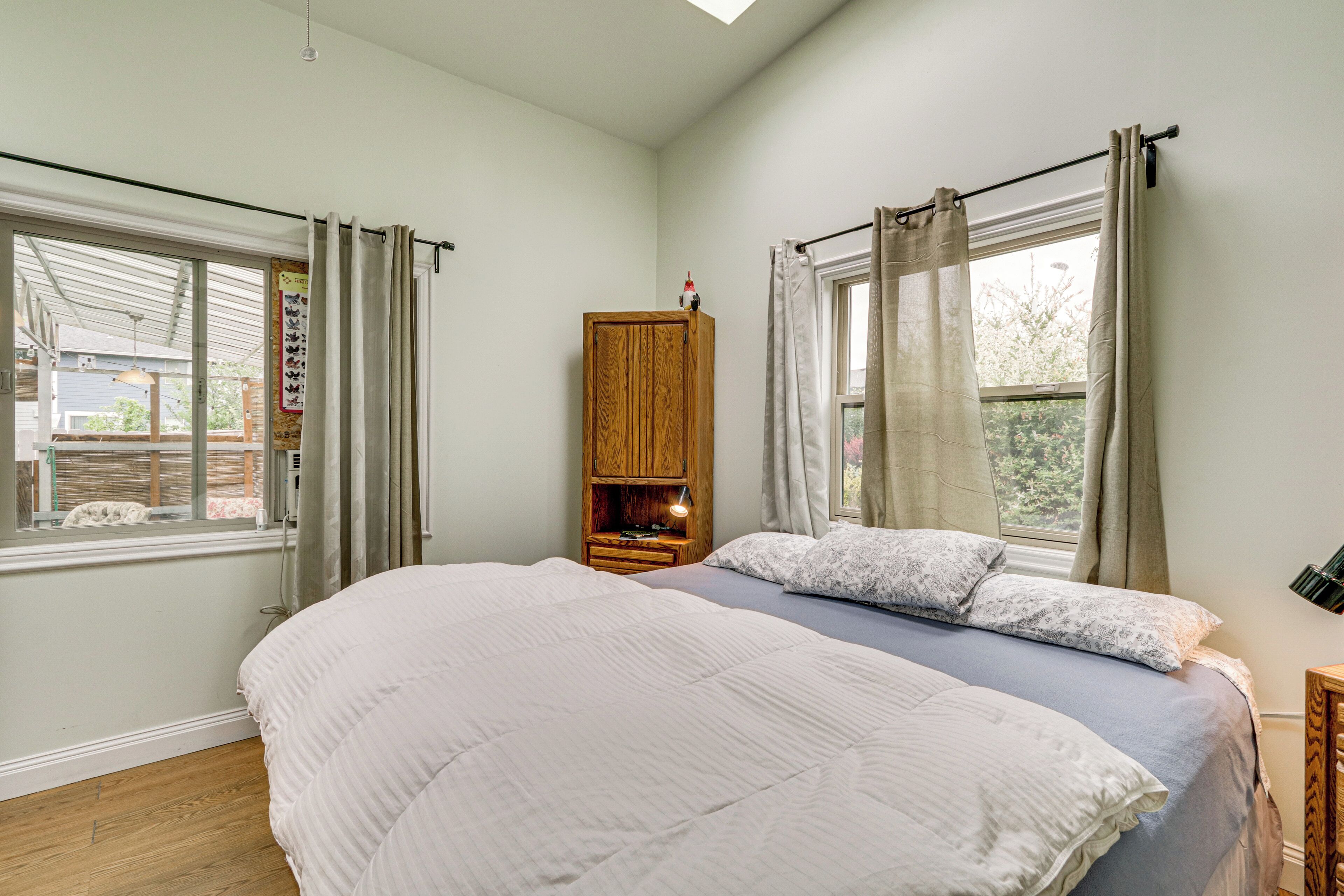 A bedroom with a large bed, a wooden cabinet, and a window with curtains.