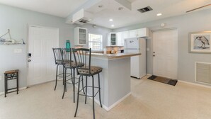 A modern kitchen with a central island, bar stools, and a refrigerator. - 30-Day Retreat Near Siesta Key | Pet Friendly (Sarasota)