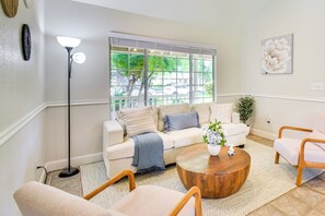 A living room with a beige sofa, a round wooden coffee table, and a floor lamp. - Clovis Family Home: Private Pool, Near Old Town! (Clovis)