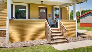 Ein Haus mit Veranda, Holzstufen und einer kleinen Sitzecke im Freien.