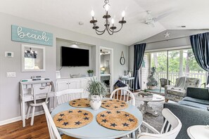 A well-lit living room with a dining area, a TV mounted on the wall, and a large window with curtains. - Pool Access & Golf View: Myrtle Beach Retreat! (Myrtle Beach)