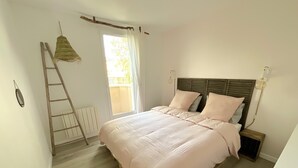 Un dormitorio con cama, una escalera, una ventana y un radiador.