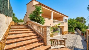 A two-story building with a balcony, a staircase, and a paved area. - 15 minutes by car / Sitges – Villa Ilus. XXL Pool, A/C by Weekly Villas 12 P (Sitges)