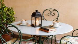 A round table with two white cups of coffee, a lit candle in a lantern, and a stack of books. - 15 minutes by car / Sitges – Villa Ilus. XXL Pool, A/C by Weekly Villas 12 P (Sitges)