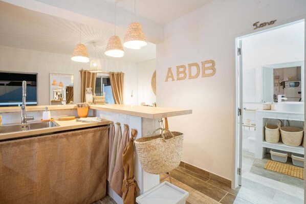 A modern kitchen with a built-in island, pendant lighting, and a wall-mounted sign reading "ABDB".